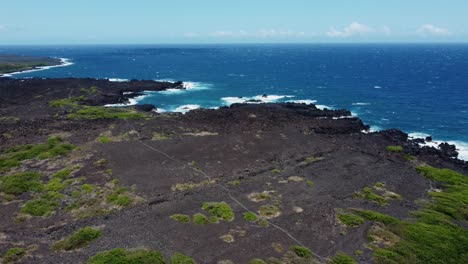 cinematic crane drone shot of deep blue ocean waves crashing on lava rock near volcano national park on the big island of hawaii