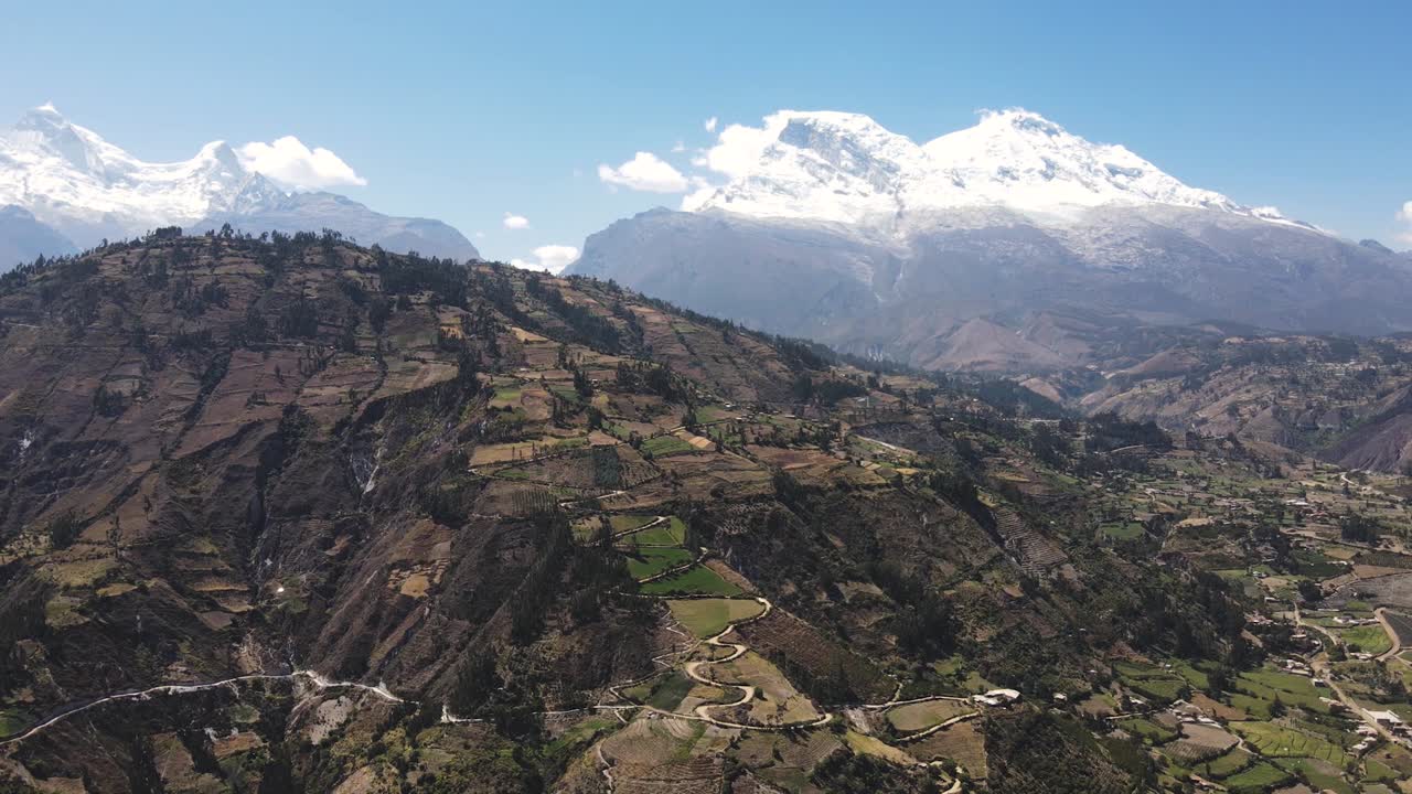 toma panorámica de una colina verde con un pico nevado en el fondo y un valle en las tierras altas de perú