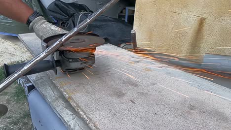 4k slow motion video of a worker sharpening a long metal bar with a radial saw producing hundreds of orange sparks