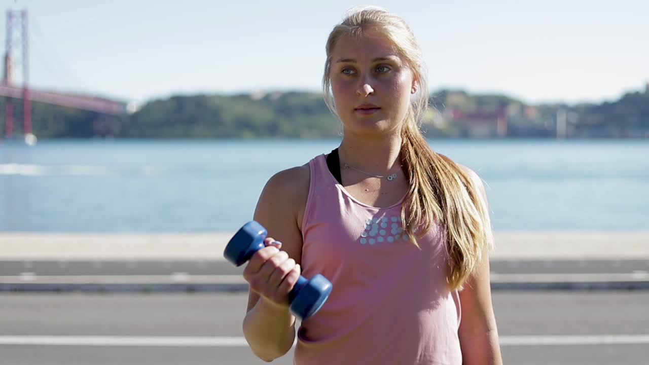 mujer joven deportiva haciendo ejercicio con pesas a orillas del río.