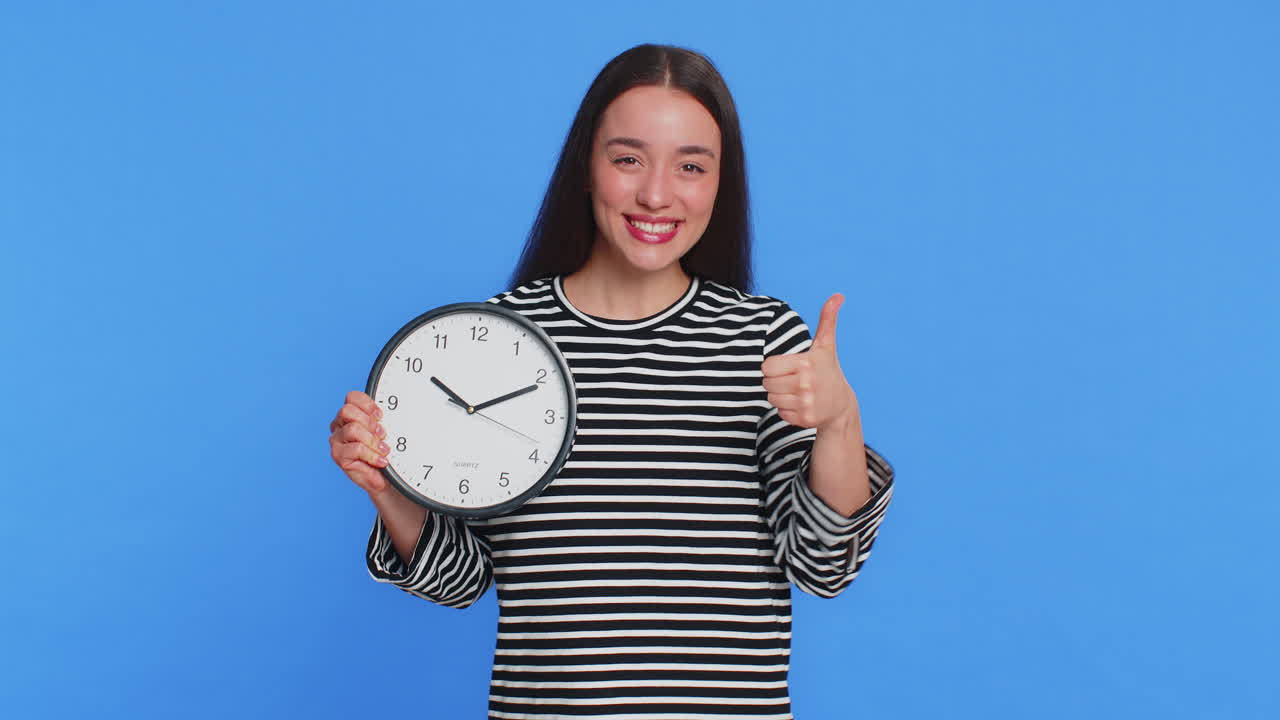Caucasian woman showing time hour on wall office clock ok thumb up approve hurry up deadline