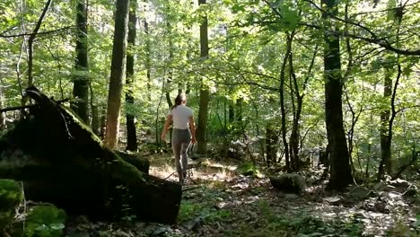 niña con una cola de caballo con polainas grises y camiseta blanca caminando en un bosque profundo en un hermoso día de finales de verano, slomo, pan a la derecha