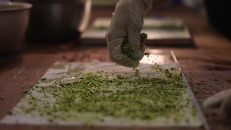 Pastry-chef-with-gloved-hand-sprinkles-the-dessert-dough-with-seeds