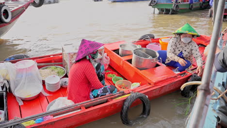 dos mujeres haciendo comida de fideos vietnamitas navegando en el mercado local de botes flotantes