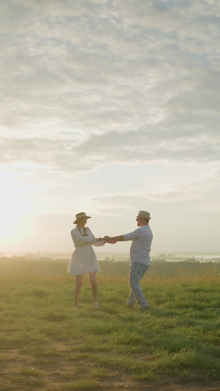 한 부부는 평온한 호수 에 있는 잔디로 인 언덕에서 해가 지는 동안 기게 회전한다. 남편은  셔츠와 모자를 입고 색 드레스를 입은 아내를 포옹한다.