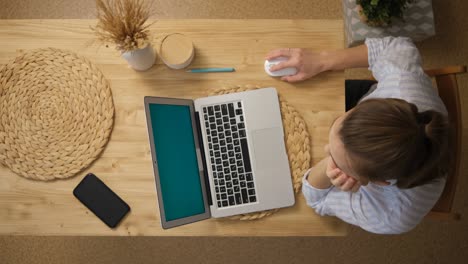 the girl is surfing the internet. and sits in social networks instead of remote work and conferences. a laptop with a green screen. top view. remote work