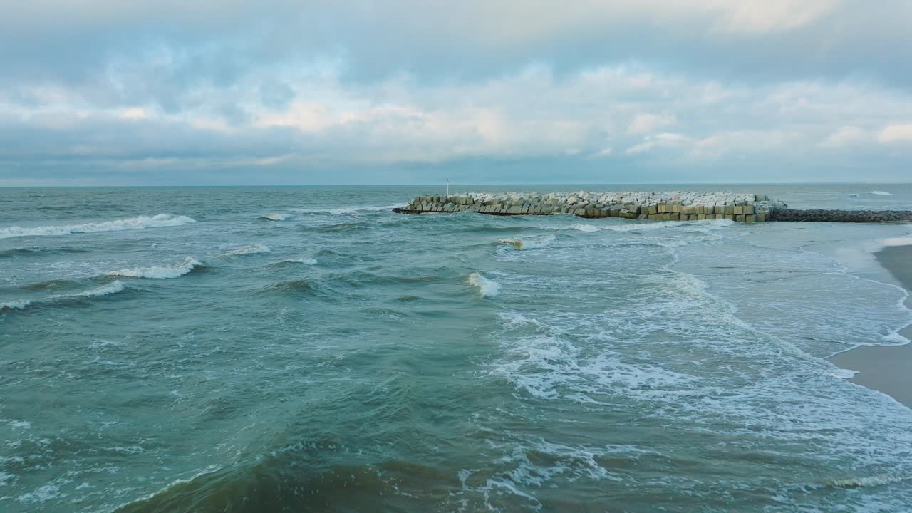 라트비아 리파자(liepaja)에 있는 발트해 연안에 콘크리트 블록과 바위가 있는 보호용 돌 부두의 공중 설정 전망, 해안 침식에 대한 해변 강화, 드론 샷이 뒤로 이동