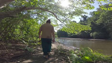 woman walks along the blue river in raja ampat, indonesia