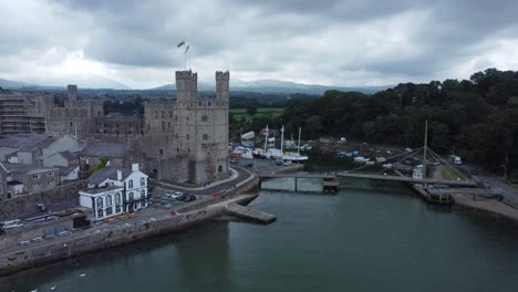 ancient caernarfon castle welsh harbour town aerial view medieval waterfront landmark orbiting right shot