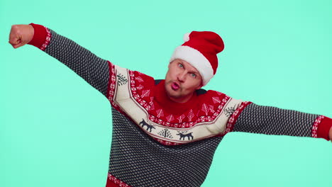 crazy man in sweater santa christmas hat demonstrating tongue out, fooling around making silly faces