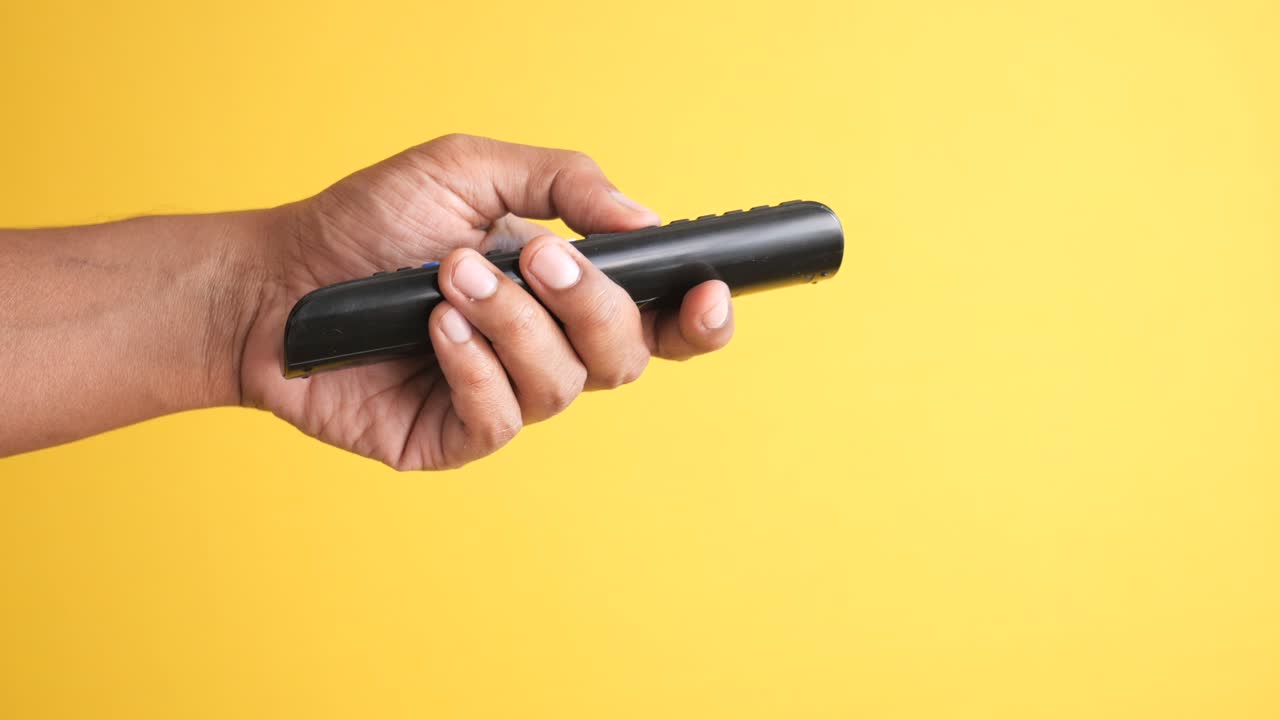 Cerca de la mano del hombre sujetando el control remoto del televisor
