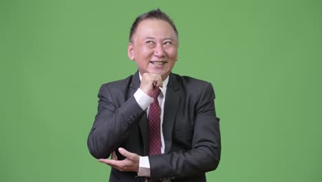 mature happy japanese businessman smiling while thinking