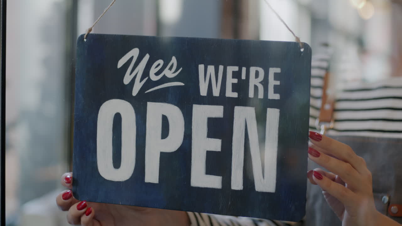 Woman Hanging Closed Sign on Store Window