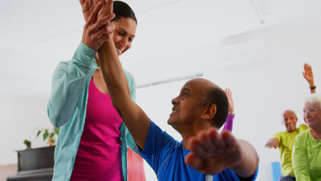 Vista-Frontal-De-Una-Entrenadora-Caucásica-Entrenando-A-Un-Hombre-Mayor-En-Ejercicio-En-El-Gimnasio-4k