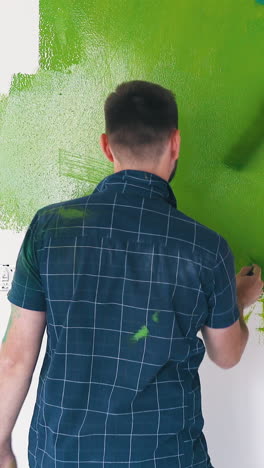 lovely young man in blue shirt and smiling woman in red paint white wall with word love in repairing room backside view