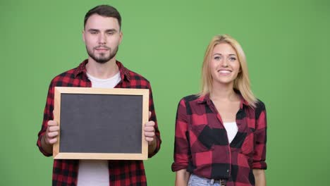 young couple holding blackboard and giving thumbs up together