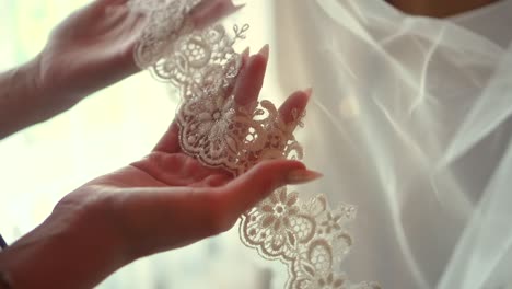 the bride strokes a white veil with her hand