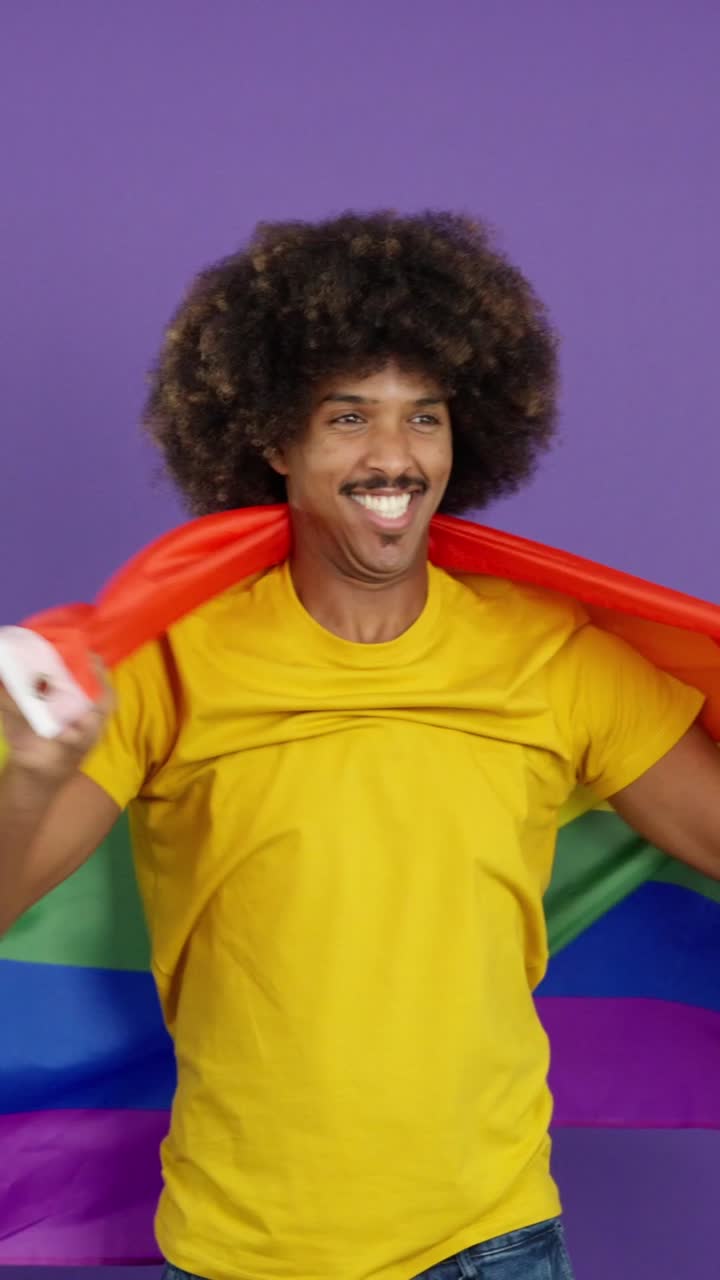 Person draped in a rainbow flag smiling
