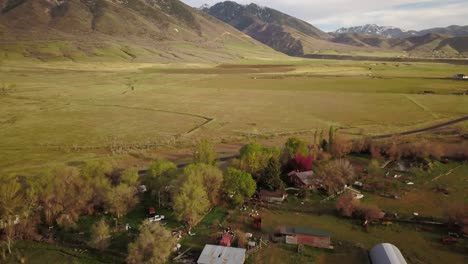 drone view of a ranchers land with a sun setting behind the mountain range