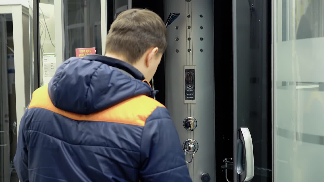 un joven examina las cabinas de ducha en la tienda de materiales de construcción