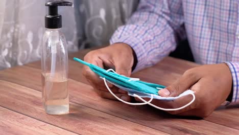 person inspecting a face mask and using hand sanitizer