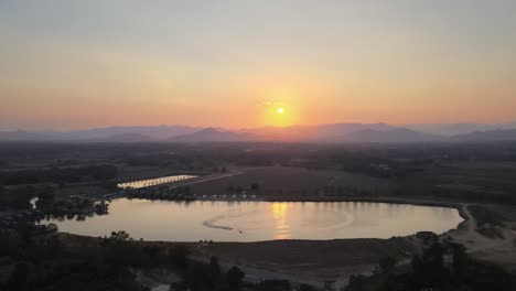 aerial drone shot of a beautiful drone shot with a sunset and jet skis on a lake