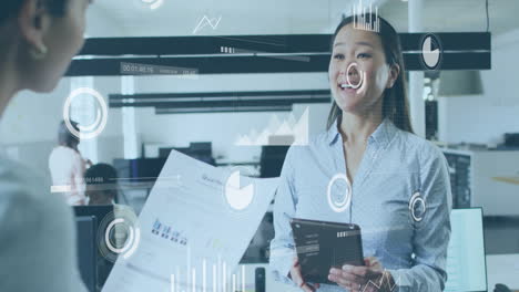 using animation, businesswoman discussing data with colleague on tablet in office