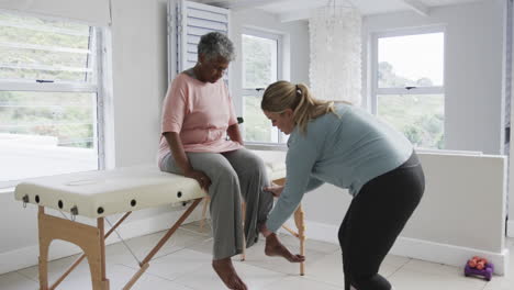 caucasian female physiotherapist checking leg of senior woman, copy space, slow motion