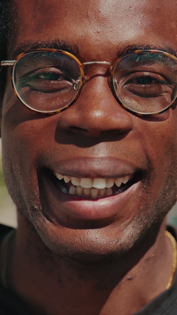 Primo piano di giovane uomo di colore sorridente con gli occhiali