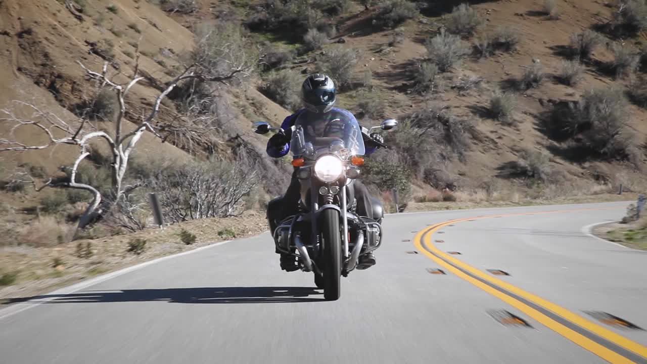 Un uomo guida una moto lungo una strada di montagna.