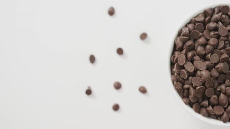 Video-of-overhead-view-of-bowl-of-chocolate-chip-over-white-background