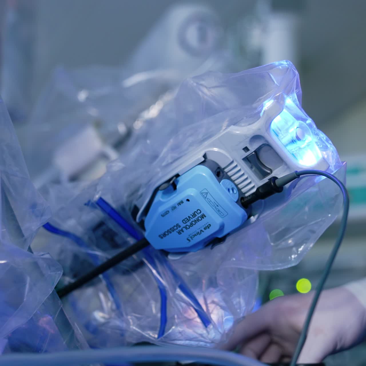 Part of the Da Vinci robot coated in plastic. Medic stand beside the equipment monitoring the procedure