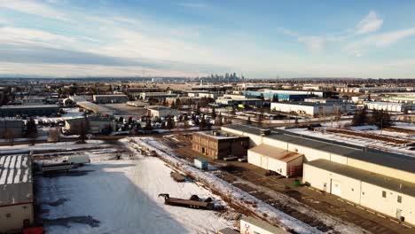 flying over winter warehouses with a view of downtown calgary, alberta, canada