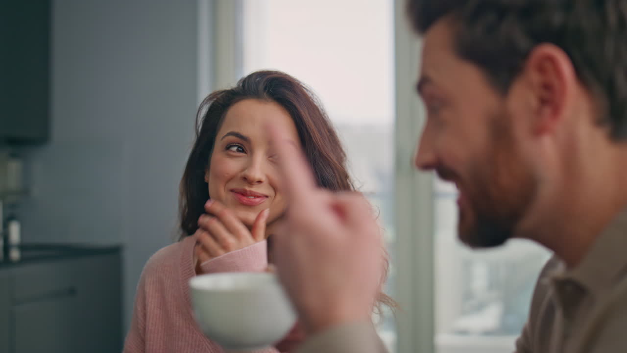 キッチンで話す愛し合う夫婦のクローズアップ。幸せそうに笑いながらコーヒーを飲む二人