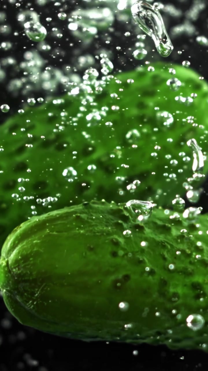 Cetrioli verdi freschi sommersi nell'acqua con bolle in risalita