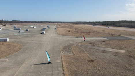 aerial drone tracking shot of two land sailing buggies turning a corner of disused airfield