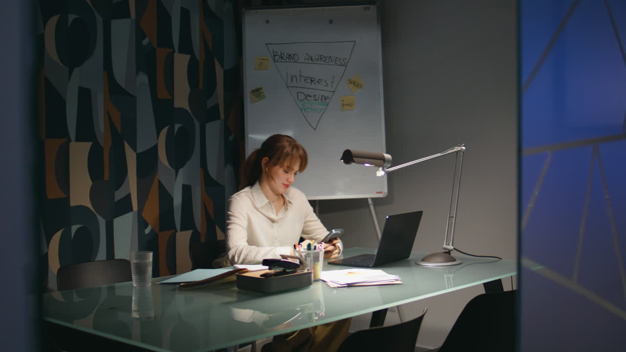 Satisfied woman messaging mobile phone in night office. Businesswoman late work