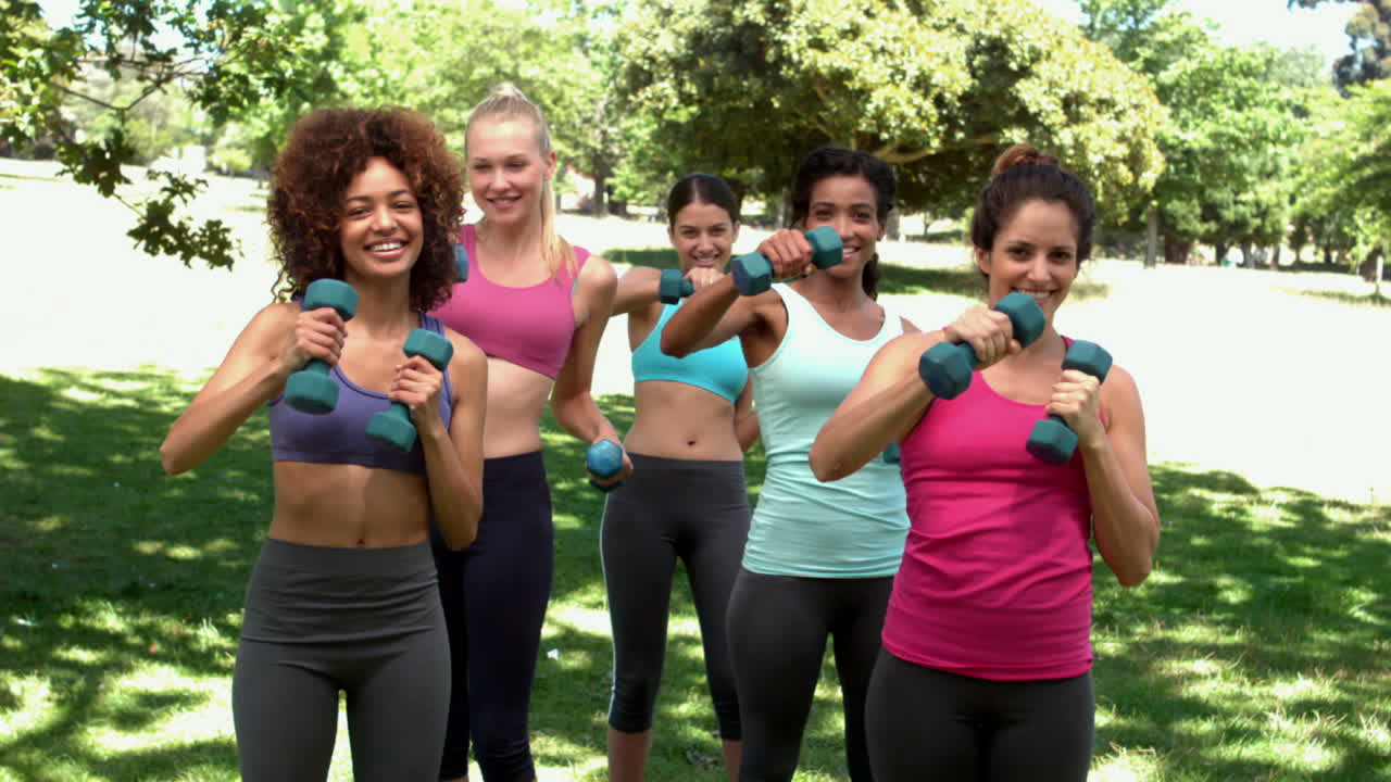clase de fitness trabajando juntos con pesas en el parque