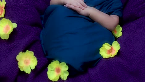 cute newborn baby sleeping in baby wrap with flowers in unique style from top angle shot