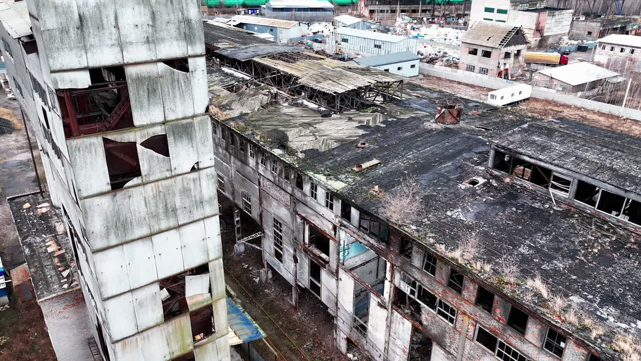 Decayed exterior of an old chemical factory complex. Grey ruined walls and roofs of the buildings from aerial perspective.