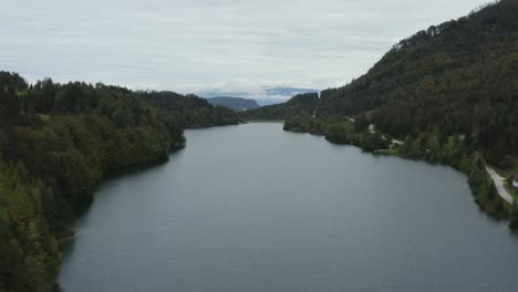 freibach reservoir at southern austrian alps country on overcast day, aerial flyover rising shot