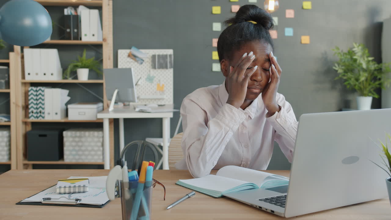 Young Woman Stressed at Laptop in Office