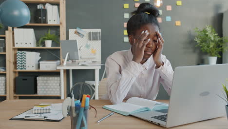 young woman stressed at laptop in office