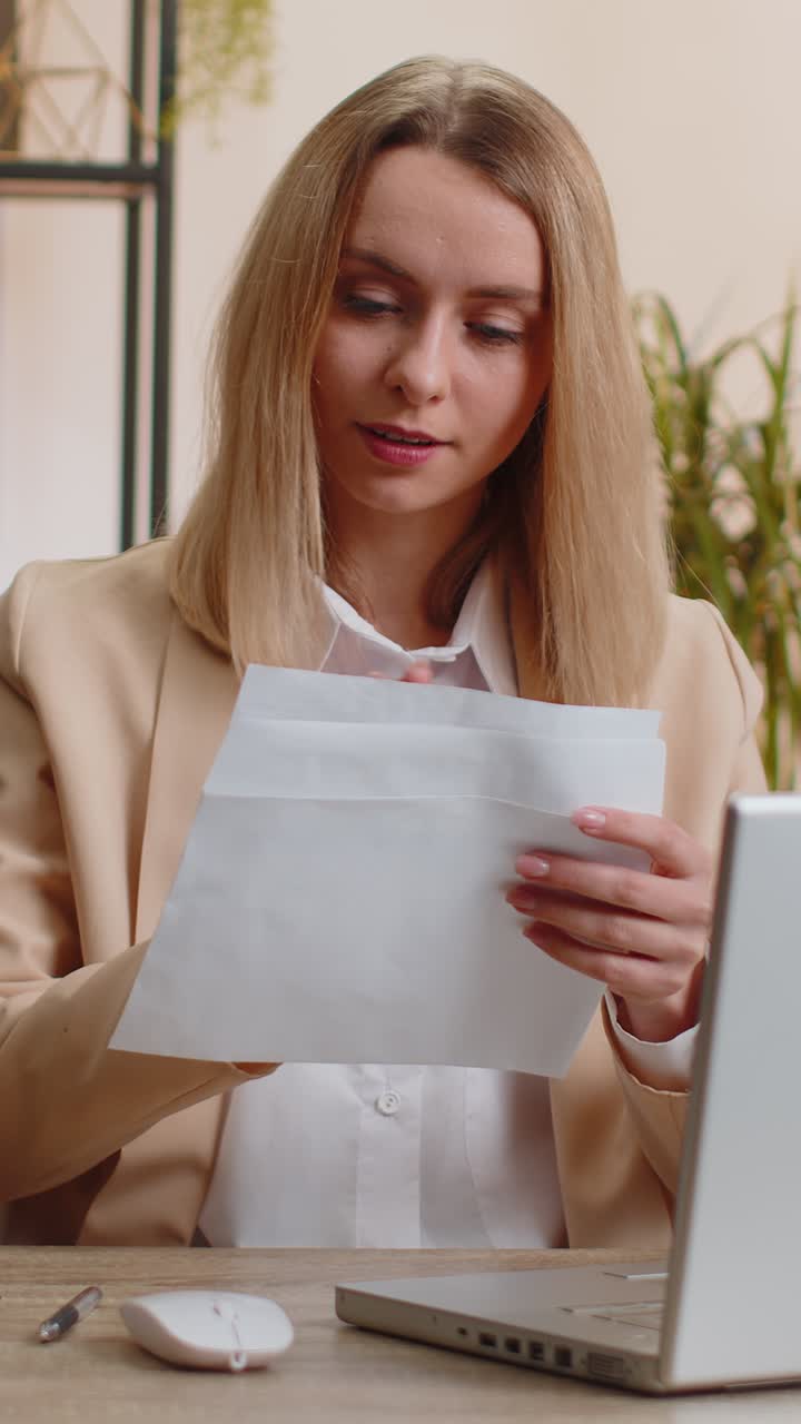 Imprenditrice apre una busta e legge una lettera riguardante crescita professionale, avanzamento di carriera, promozione o l'approvazione di un prestito bancario.