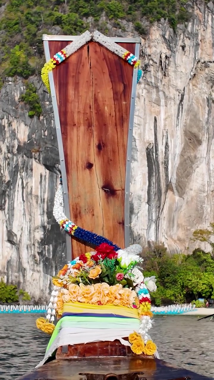 Vista ravvicinata di una tradizionale barca a coda lunga thailandese che passa scogliere calcaree spettacolari durante un giro in barca all'isola di Ko Hong, Thailandia