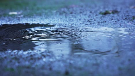 Mehrere-Wassertropfen-Fallen-In-Einer-Pfütze-Auf-Den-Beton