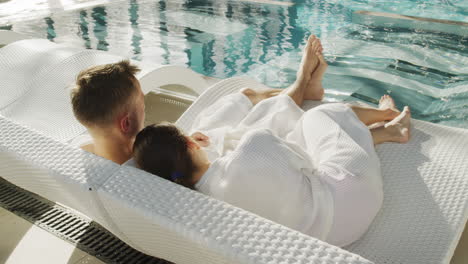 couple relaxing by the pool in bathrobes