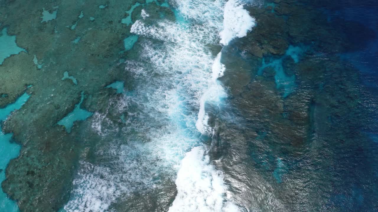 la toma del dron captura la laguna azul en todo su esplendor, mostrando las aguas cristalinas que revelan la belleza de las rocas debajo, mientras las olas rompen en el arrecife agregando una sensación de belleza natural