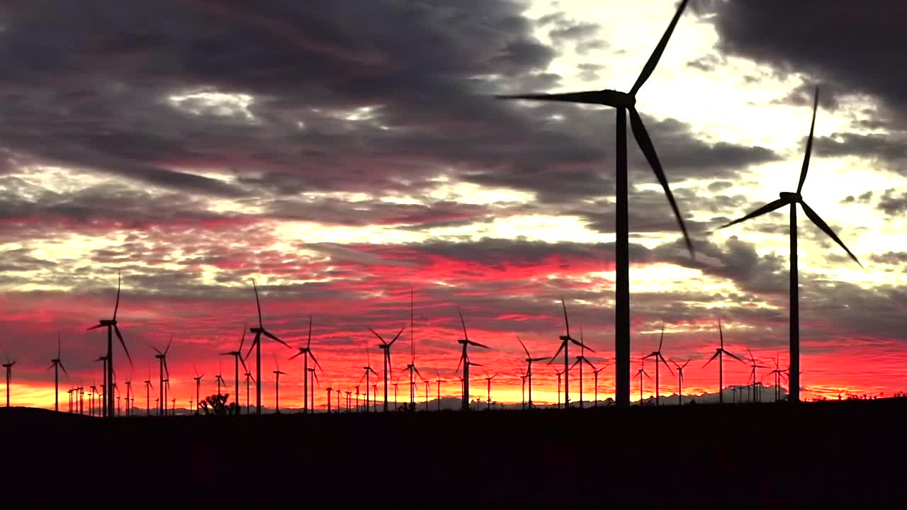 Field of Wind Turbines at sunset, beautiful red sky color, green renewable energy