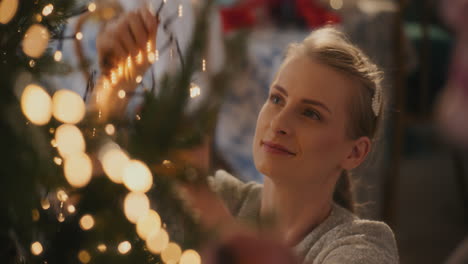 young woman adjusting glowing led lights on tree